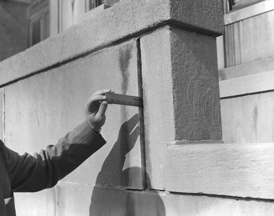 Man taking measurement of missing mortar prior to 1965 renovation.