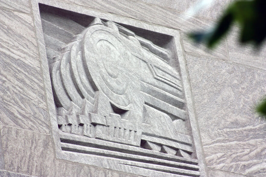 Carving on the upper area of the north and south extensions of City Hall, this is an Art Deco representation of trains, circa 2022.